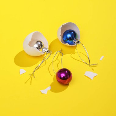 Parlak sarı arka planda yumurta kabuğu içinde noel topları olan yaratıcı bir düzen. Görsel trend. Noel konsepti. Minimalist estetik, gölgeli bir hayat. Yeni fikir.