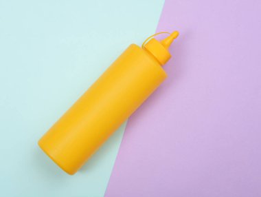 Pastel arka planda sarı plastik hardal şişesi.