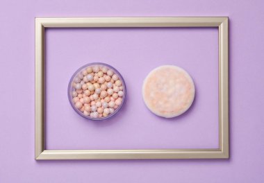 Pastel arka planda altın çerçeveli makyaj tozu topları. Asgari güzellik kavramı