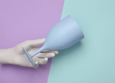 Pastel arka planda plastik şarap kadehini tutan el. Üst görünüm