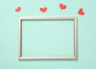 Boş altın çerçeve ve pastel mavi arka planda kalpler..