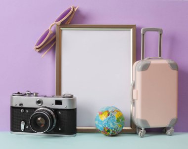 Beyaz kağıt kaplamalı fotoğraf çerçevesi (model) ve pastel arka planda seyahat dekoru. Minimal natürmort. Boşluğu kopyala