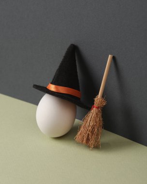 Yaratıcı cadılar bayramı planı. İki ton arkaplanda cadı şapkası ve süpürgesi olan bir yumurta. Kavramsal patlama. En az yaşam süresi.
