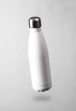 Beyaz termal şişe, gri arka planda, gölgeli havada süzülüyor.