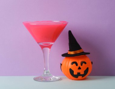 Yaratıcı cadılar bayramı düzeni, neon sümüklü kokteyl bardağı ve iki ton pastel arka planda cadı şapkalı balkabağı. Görsel trend. Minimalist estetik natürmort hayat.