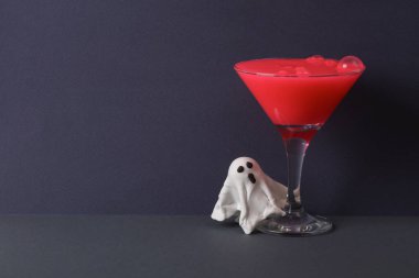 Yaratıcı cadılar bayramı düzeni, neon sümüklü kokteyl bardağı ve iki ton koyu arka planda hayalet. Görsel trend. Minimalist estetik natürmort hayat.