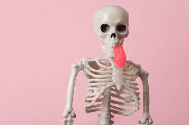 Ağzı sümüklü, pembe arka planı olan bir iskelet. Yeni bir fikir. Minimalizm cadılar bayramı kavramı