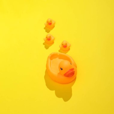 Kauçuk ördek anne ve ördek yavrularıyla yaratıcı bir düzen. Parlak sarı arka plan ve gölge. Görsel yaz trendi. Minimalist estetik natürmort. Yeni fikir.