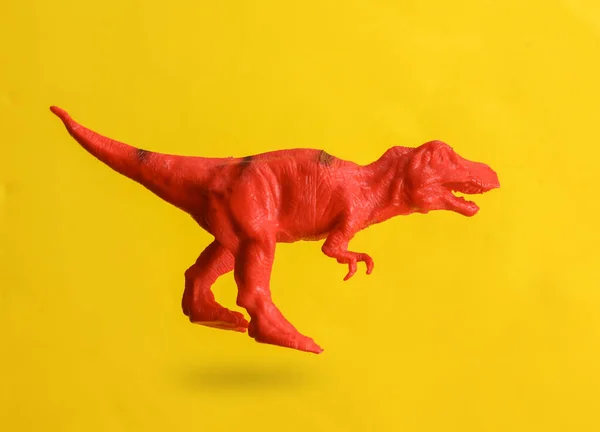 影と黄色の背景に浮かぶプラスチックティラノサウルス — ストック写真