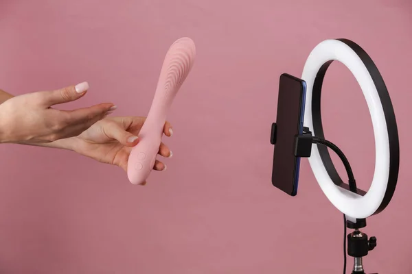 セックスブログ 女性の手は振動子を保持し ピンクの背景にLedリングランプとスマートフォンのカメラに放送 — ストック写真