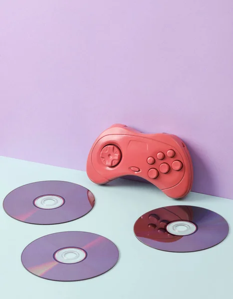 Cdディスクとパステルの背景にレトロゲームパッドと創造的なレイアウト 概念的なポップ 最小限の静物 — ストック写真