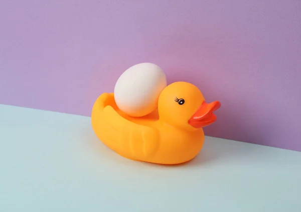 Creative layout with rubber duck and egg on pastel background. Conceptual pop. Minimal still life.