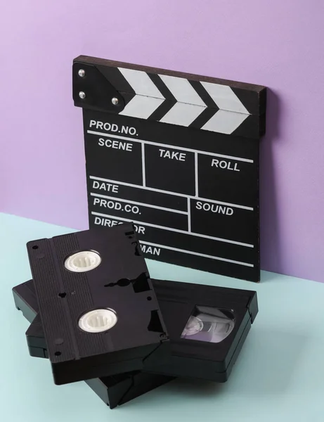 Creative retro 80s layout with vhs video cassette, movie clapperboard on pastel background. Conceptual pop. Minimal still life