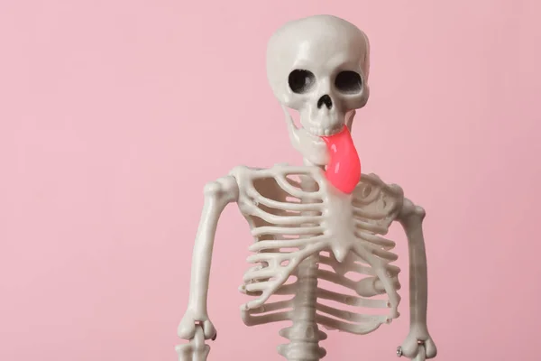 Skeleton with slime in the mouth on pink background. Fresh idea. Minimalism halloween concept