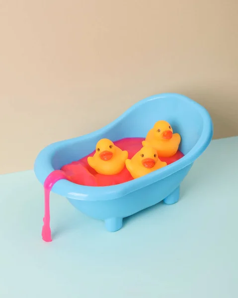 stock image Creative layout, toy bathroom sink with rubber ducks and neon slime on two tone pastel background. Visual trend.