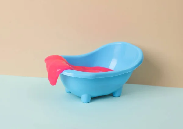 stock image Creative layout, toy bathroom sink with neon slime on two tone pastel background. Visual trend.