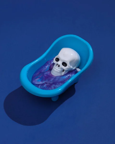 在布局和玩具浴室之间 有着富有创意的哈洛布局 带有骨架的玩具浴室水池和深蓝色背景的黏液 视觉趋势 — 图库照片