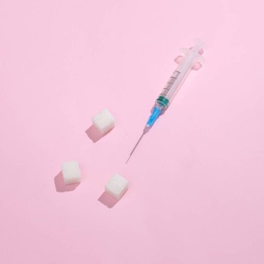 Parlak pembe arka planda küp şekerli şırınga. Diyabet. Asgari ilaç konsepti