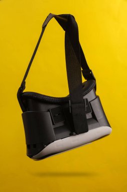 Sanal gerçeklik miğferi sarı arka planda gölgeli havada süzülüyor