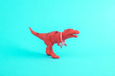 Oyuncak kırmızı dinozor tyrannosaurus rex ve turkuaz arka planda kulaklıkları var. Minimalizmin yaratıcı düzeni