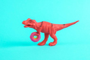 Oyuncak kırmızı dinozor tyrannosaurus rex ve turkuaz bir arka plan. Minimalizmin yaratıcı düzeni