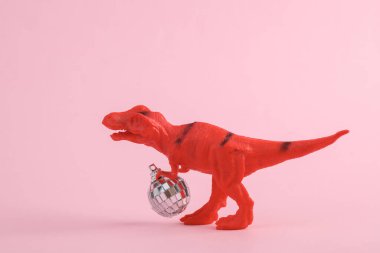 Pembe arka planda disko topu olan iki dinozor tyrannosaurus rex. Minimalizmin yaratıcı düzeni. Parti konsepti