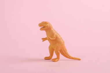 Oyuncak dinozor Tyrannosaurus Rex pembe arka planda. Minimalizmin yaratıcı düzeni