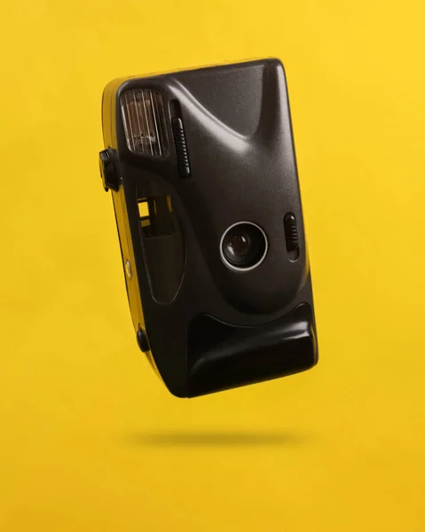影と黄色の背景に浮かぶプラスチックレトロカメラ — ストック写真