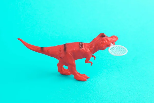 Spielzeug Roter Dinosaurier Tyrannosaurus Rex Mit Tennisschläger Auf Türkisfarbenem Hintergrund — Stockfoto
