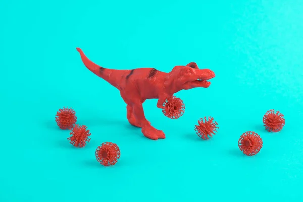 Toy red dinosaur tyrannosaurus rex with virus strain on a turquoise background. Minimalism creative layout
