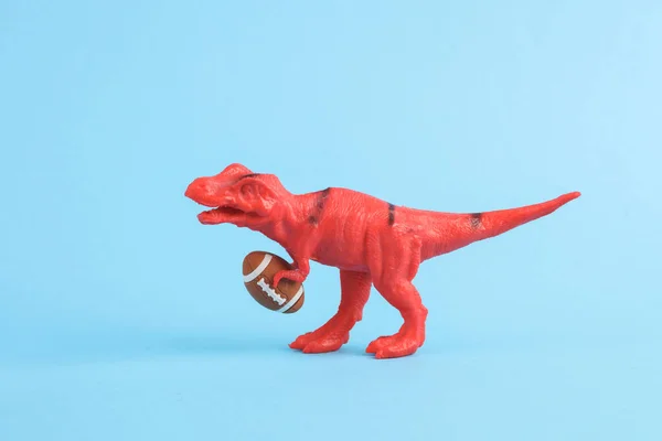 Brinquedo Dinossauro Tyrannosaurus Rex Com Bola Rugby Fundo Azul Layout — Fotografia de Stock