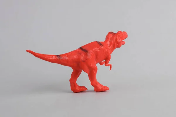 Toy red dinosaur tyrannosaurus rex on gray background. Minimalism creative layout