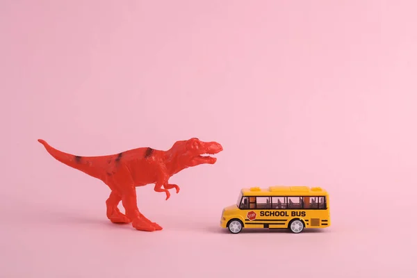 Spielzeug Zwei Dinosaurier Tyrannosaurus Rex Mit Schulbus Auf Rosa Hintergrund — Stockfoto