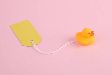 Pembe arka planda fiyat etiketi olan lastik ördek. Minimalizmin yaratıcı düzeni