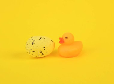 Sarı arka planda paskalya yumurtası olan lastik ördek.