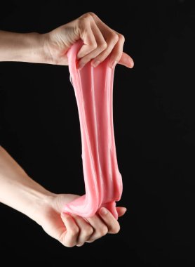Siyah arka planda pembe balçık tutan kadın eller.