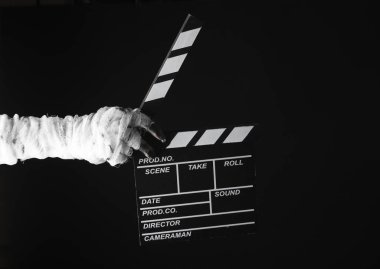 Annenin eli bandaja sarılı ve siyah arka planda izole edilmiş bir film klasörü tutuyor. Cadılar Bayramı, film konsepti