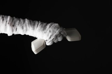 Annenin eli bandaja sarılı ve siyah arka planda izole bir telefon tüpü tutuyor. Cadılar Bayramı konsepti