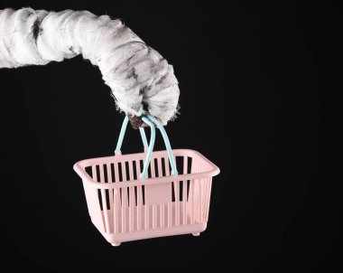 Mumya el ele tutuşma süpermarket sepeti siyah arka planda izole. Cadılar Bayramı, alışveriş konsepti