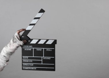 Annenin eli bandaja sarılı ve gri arka planda izole edilmiş bir film klasörü tutuyor. Cadılar Bayramı, film konsepti