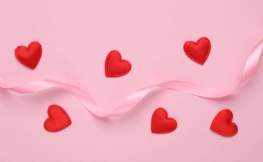 Pembe arka planda saten kurdeleli bir sürü kalp. Aşk, romantik konsept