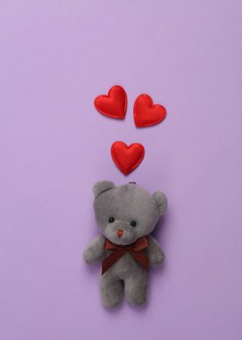 Mor arka planda kalpleri olan bir oyuncak ayı. Aşk, Sevgililer Günü konsepti