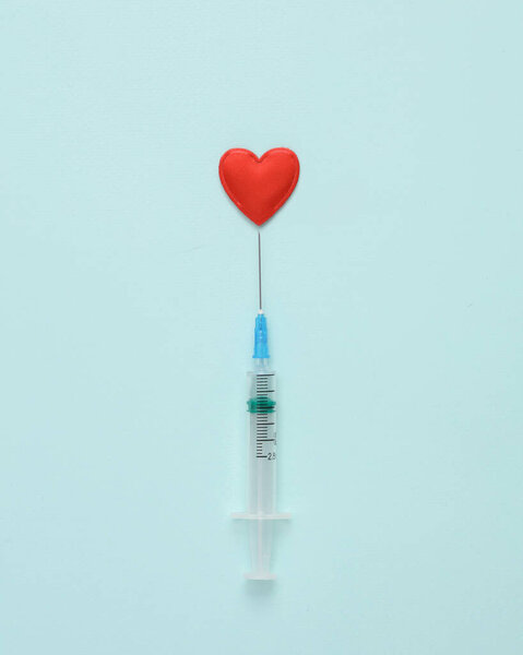Syringe with a heart on a blue background. Love concept. Minimal layout