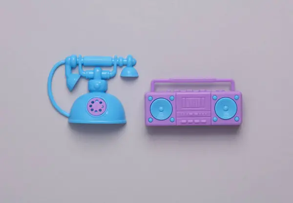 グレーの背景におもちゃのプラスチックのボムボックステープレコーダーとロータリー電話 — ストック写真