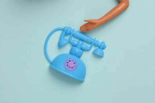 おもちゃ青の背景にレトロなロータリー電話と人形の手 — ストック写真