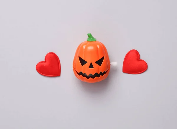 Halloween clockwork pumpkin head with hearts on gray background