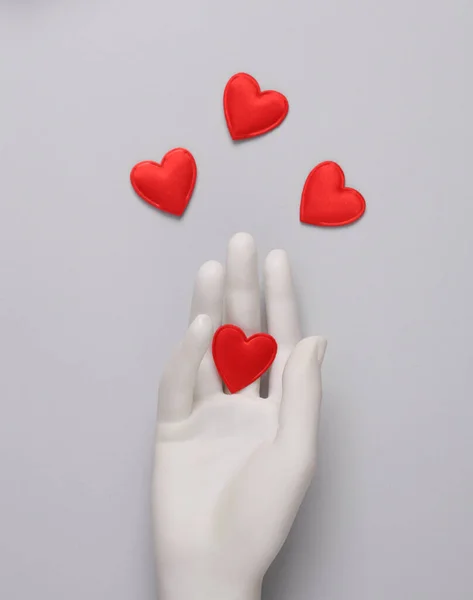 Mannequin hand with hearts on a gray background. Valentine's day concept