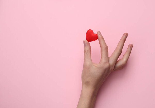 Женская рука с сердцем на розовом фоне. День святого Валентина