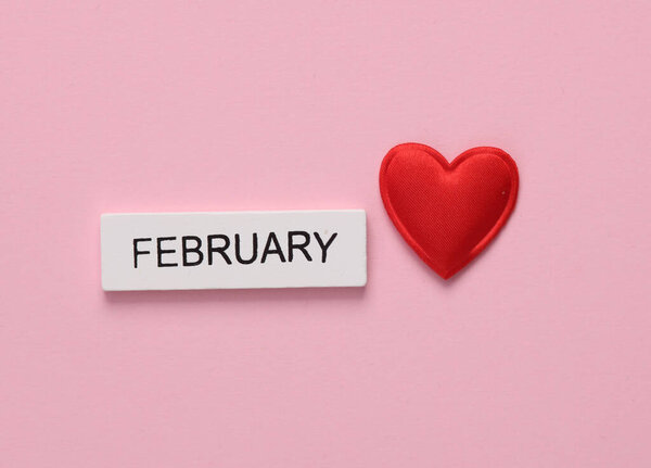 February wooden calendar with heart on pink background. Valentine's Day