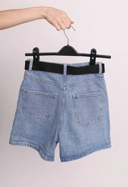 Vrouwelijke Hand Houdt Een Hanger Met Blauwe Denim Shorts Met — Stockfoto